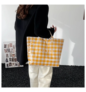 Detailed view of yellow plaid tote bag with TOTE BAG lettering and glossy finish