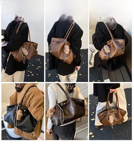 Detail view of large leather tote bag with pleated texture and plush bear charm accessory