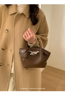 Detail of dark brown lychee leather handbag with silver buckle and mini leather charm