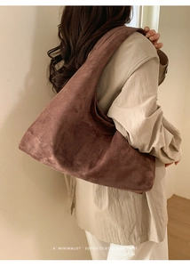 Détail d'un grand sac hobo en daim marron chocolat porté de côté sur un mannequin femme