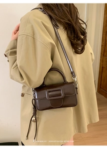 Close-up of retro brown patent leather square bag with large buckle and metal charm