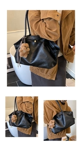 Detail of a large black leather tote bag with a cute plush bear pendant accessory