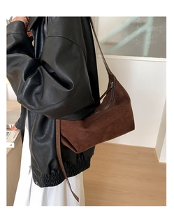 Detail of a dark brown frosted suede half-moon shoulder bag worn over a black leather jacket