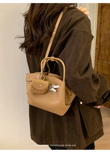 Close-up of khaki lychee texture leather shoulder bag with a mini saddle charm on a model