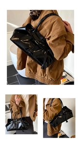 Close-up of black glossy oil wax leather tote with metallic buckle and shoulder strap