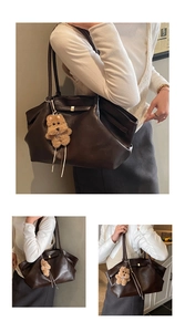 Detail of dark brown tote bag with smooth faux leather texture and plush bear pendant