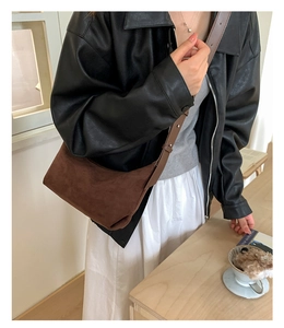 Détail d'un sac à bandoulière en daim marron avec texture mate et sangle réglable