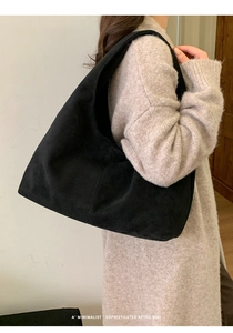 Sac hobo minimaliste en daim noir porté par un mannequin au style rétro sophistiqué