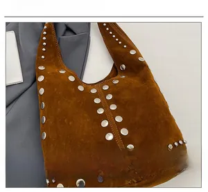 Dettaglio dei rivetti in argento su una borsa tote in pelle scamosciata marrone scuro