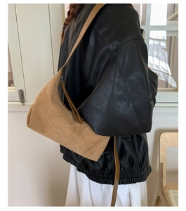 Brown suede underarm bag styled with a leather jacket and white skirt on a model