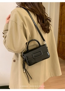Model view of black glossy patent leather crossbody bag with square buckle detail