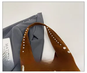 Dettaglio della comoda tracolla con borchie della borsa sottobraccio in pelle scamosciata