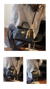 Detail of black glossy leather handbag with gold hardware and colorful beaded tassel