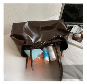 Top view of spacious brown oily leather tote bag with iPad and cosmetic essentials