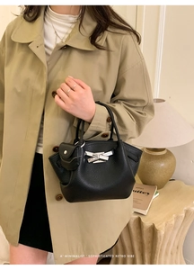 Detail of black lychee leather handbag with silver bow buckle and small pouch