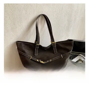 Detail of dark brown tote bag with gold lock and textured finish in a lifestyle setting