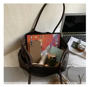 Macro shot of dark brown tote bag interior filled with iPad, smartphone and daily items