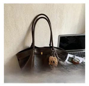Detail of a large brown leather tote bag with a plush dog charm and lifestyle items