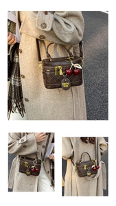 Close-up of brown quilted box bag featuring cherry charm and adjustable leather strap