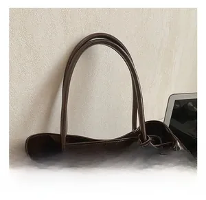Close-up of double cylindrical handles and glossy dark brown leather texture of the bag