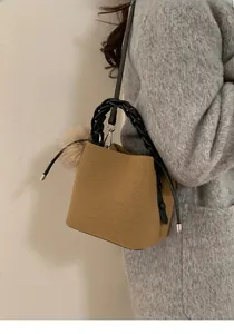 Close-up of a camel wool bucket bag with woven handle and detachable shoulder strap