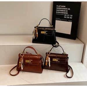 Detailed view of structured leather handbags with gold hardware and beaded charms