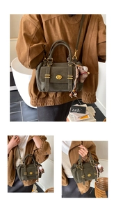Close-up of a vintage dark green crossbody bag with a matte finish and a horse charm