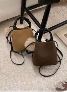 Detail of wool texture mini bucket bags with woven handles and furry pom-pom charms