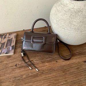 Detail of vintage dark brown faux leather square handbag with heart pendant on rustic wood