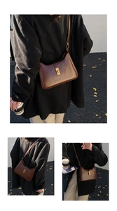 Detail of vintage brown leather underarm bag with gold metal clasp and smooth finish