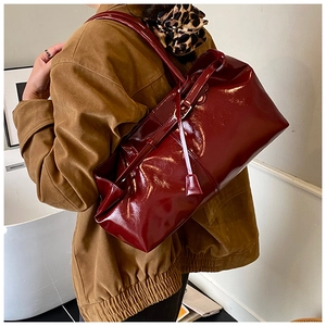Detail of burgundy glossy oil wax leather tote bag worn as a shoulder bag