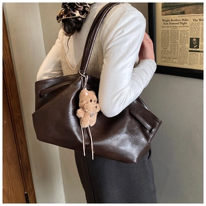 Detail of dark brown tote bag with plush bear charm and vintage aesthetic design