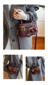 Detail view of burgundy quilted vanity bag with cherry charm and leather shoulder strap