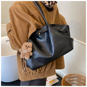 Dettaglio di una grande borsa tote vintage nera con trama in pelle e ciondolo a orsetto