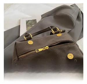 Detail of dark brown leather texture and premium gold-tone hardware on boston bag
