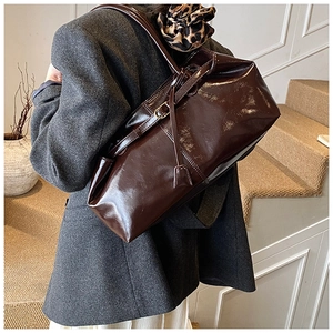 Detail of deep brown glossy patent leather tote bag showing mirror-like shine and texture