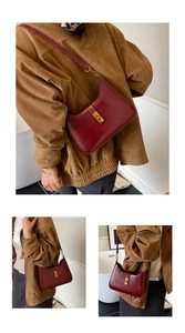Close-up of deep red leather shoulder bag featuring elegant gold metallic buckle closure