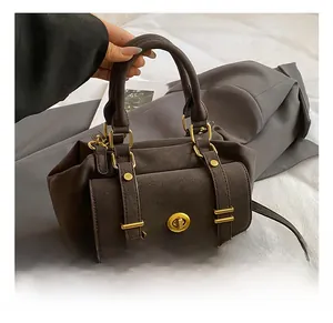Close-up of a vintage dark brown leather handbag with golden twist lock and square metal hardware