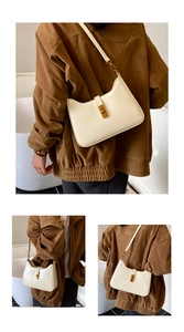 Close-up of cream leather underarm bag featuring a vintage bronze rectangular metal twist lock