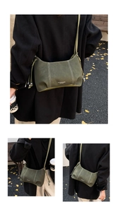 Detail of dark green hobo bag with white stitching and metal ball drawstring accent