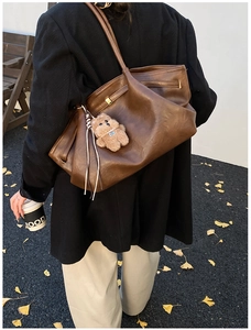Dettaglio della borsa tote marrone vintage con ciondolo a forma di orsetto peluche