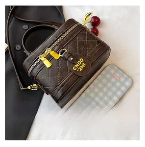 Detailed macro view of deep brown quilted cylinder bag with gold zippers and leather tag