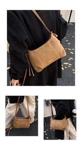 Detail of vintage brown shoulder bag with contrast stitching and long tassel charms
