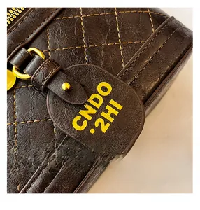 Macro shot of dark brown quilted leather texture with yellow stitching and gold hardware