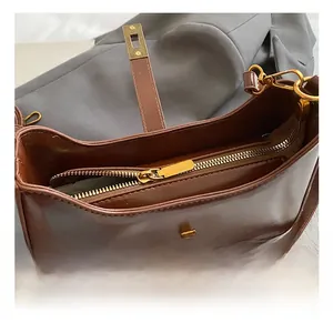 Detail view of smooth brown leather shoulder bag with premium golden metal turn-lock and zipper