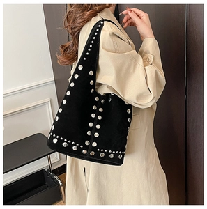 Dettaglio della borsa hobo in pelle scamosciata nera con borchie argentate indossata con cappotto