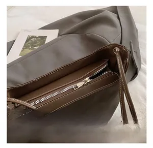Detailed close-up of dark brown leather shoulder bag with premium silver metal zipper