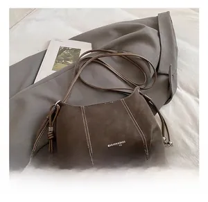Detail of dark brown leather crossbody bag with white contrast stitching and beads