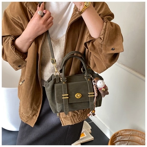 Detail of dark green suede messenger bag with gold twist lock and brown horse charm