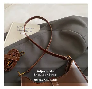 Detail of adjustable leather strap and vintage hardware on dark brown underarm bag